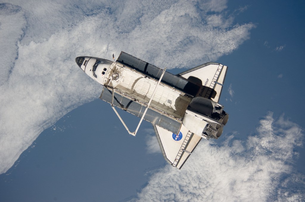 View of the space shuttle against the blue and white Earth.