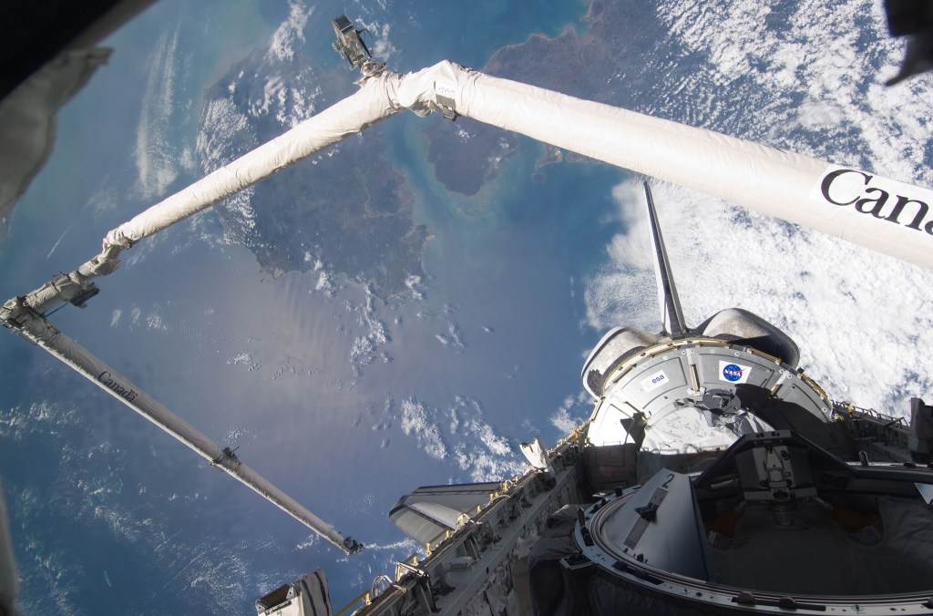 Image of the shuttle's robotic arm against the background of the Earth.