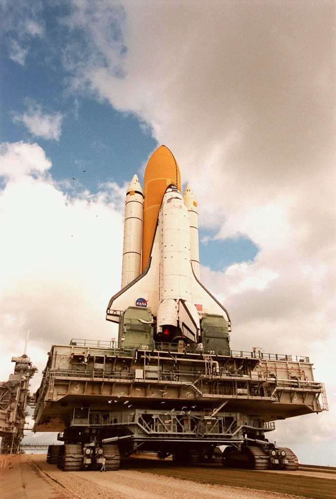 Image of a space shuttle stack on its mobile launcher on its way to the launch pad.