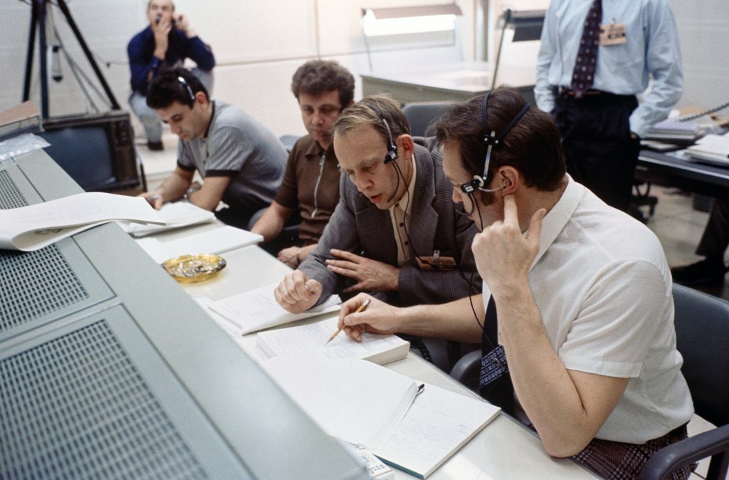 Image of several men sitting at consoles in a control center.