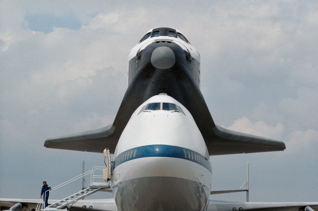 Head on view of a space shuttle orbiter sitting on top of a Boeing 747 shuttle carrier aircraft.