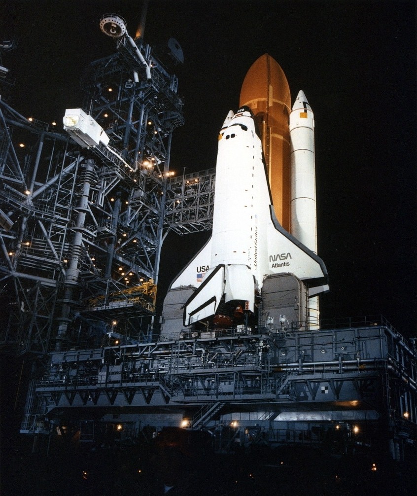 Night view of a space shuttle on its launch pad.