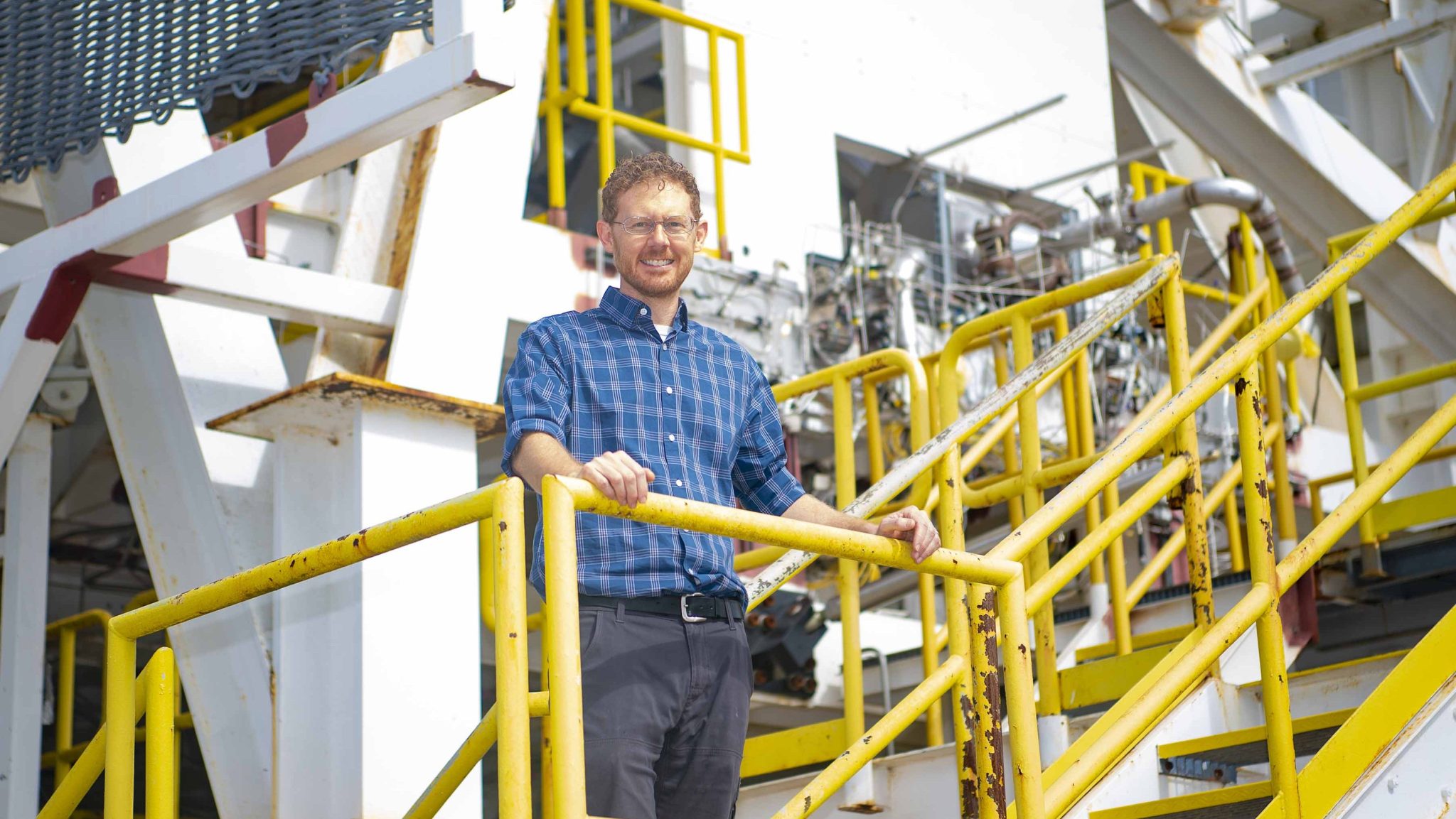 a man wearing a blue and white striped shirt stand on the E Test Complex stairs