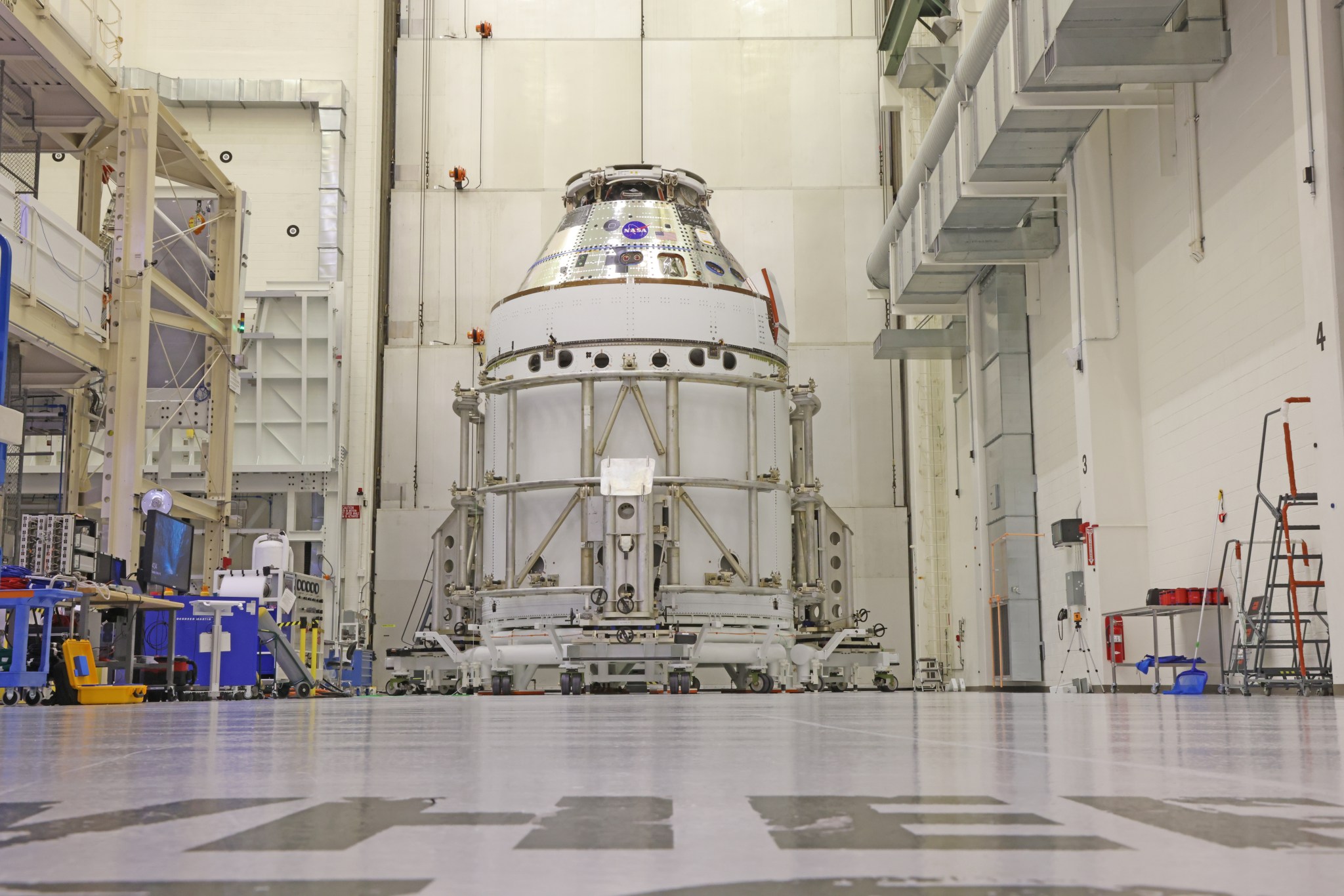 The Artemis II Orion spacecraft sits in the transfer aisle in the Neil A. Armstrong Operations and Checkout Building at NASA’s Kennedy Space Center in Florida following the installation of three spacecraft adapter jettison fairings on Wednesday, March 19, 2025. The fairings encapsulate the service module protect the solar array wings, shielding them from the heat, wind, and acoustics of launch and ascent, plus help redistribute the load between Orion and the massive thrust of the SLS (Space Launch System) rocket during liftoff and ascent. Once the spacecraft is above the atmosphere, the three fairing panels will separate from the service module reducing the mass of the spacecraft.