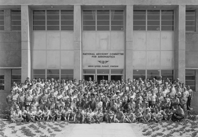 Black and white photograph of a large group of people standing in front of a building.