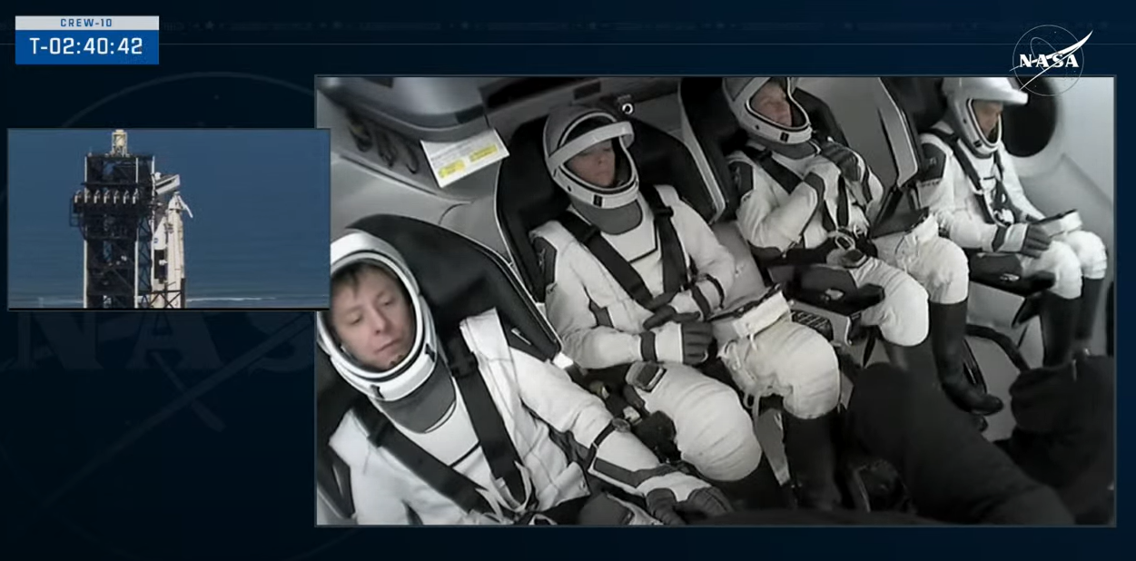 Image shows three astronauts and a cosmosnaut inside the SpaceX Dragon spacecraft.