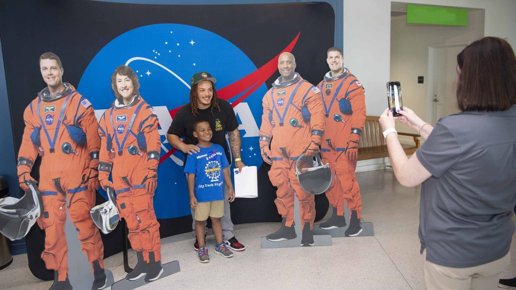 a man and young boy poses with astronauts standees