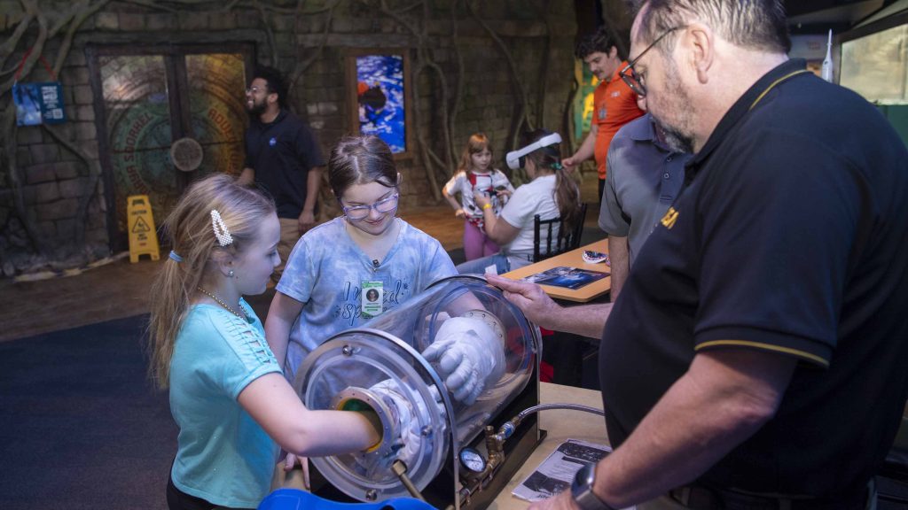 two young girls share activity provided by NASA Stennis at the Audubon Aquarium