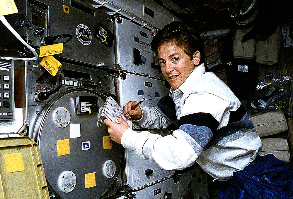 Image of a female astronaut working on an experiment in the shuttle middeck.