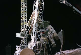 Onufriyenko (left) and Usachev traverse an existing truss on the Kvant module with a folded truss in tow.