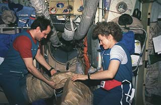 Usachev (left) and Astronaut Shannon Lucid (right) pack up some gear in the Base Block module.