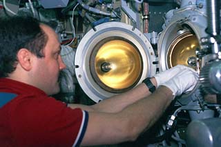 Mir-21 flight engineer Yury Usachev inserts metal samples into the QUELD furnace. 