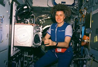 Astronaut Shannon Lucid is photographed floating beside the microgravity glovebox in the Priroda module.