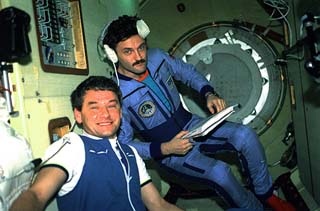 Korzun (left) and Mir-22 flight engineer Alexander Kaleri (wearing headphones) wait in the entrance to the docking module for hatch opening. 