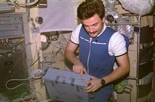 Mir-22 flight engineer Alexander Kaleri looks over a stowage box in the Base Block module.