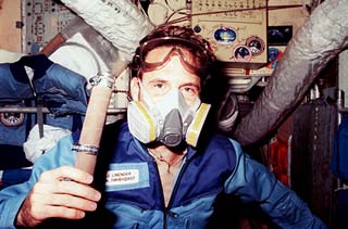 NASA/Mir-23 researcher Jerry Linenger wears a 3M air filter and goggles while holding a piece of tubing. 