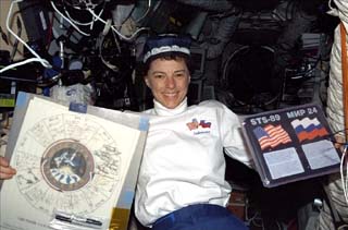 Mission Specialist Bonnie Dunbar holds the roster and STS-89/Mir-24 plaque, while wearing an Uzbeck cap. 