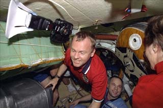 Mission Specialist Andrew Thomas passes through the airlock, entering Mir, as others observe him. 